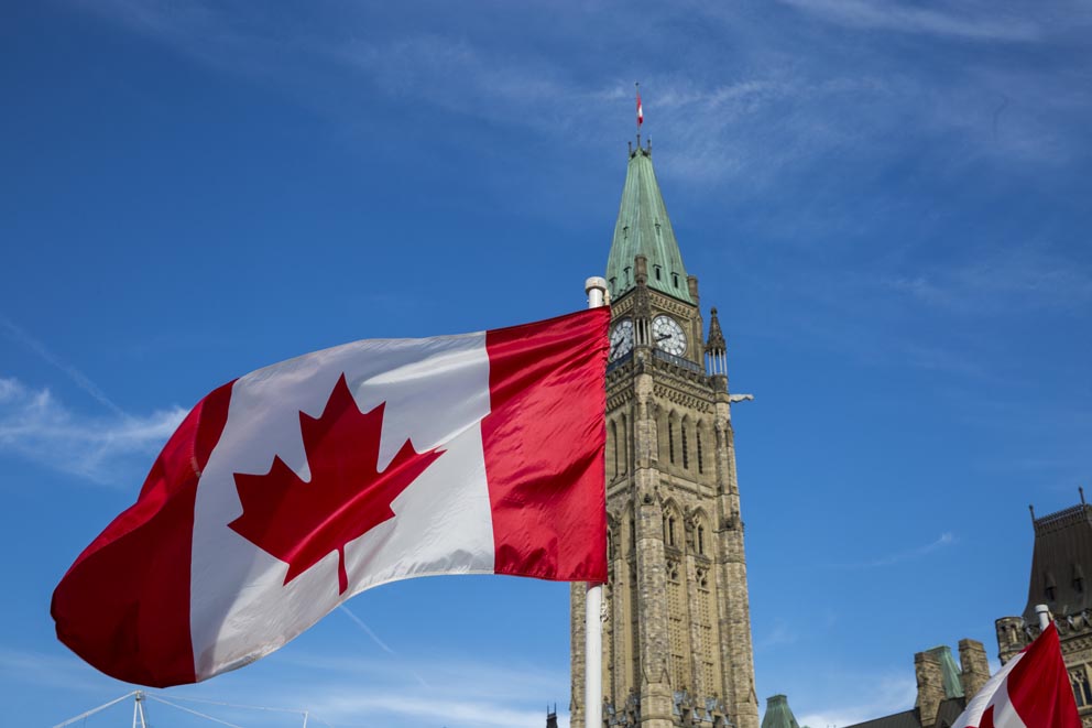 The National Flag of Canada flying on a flagpole in front of the Peace Tower in Ottawa.