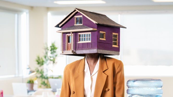 Image of a woman with a house on her head, standing next to a water cooler.