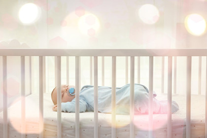 A baby asleep alone on their back in a bare crib