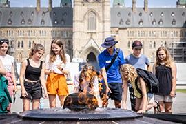 Children and an information officer look at the Centennial flame on Parliament Hill.