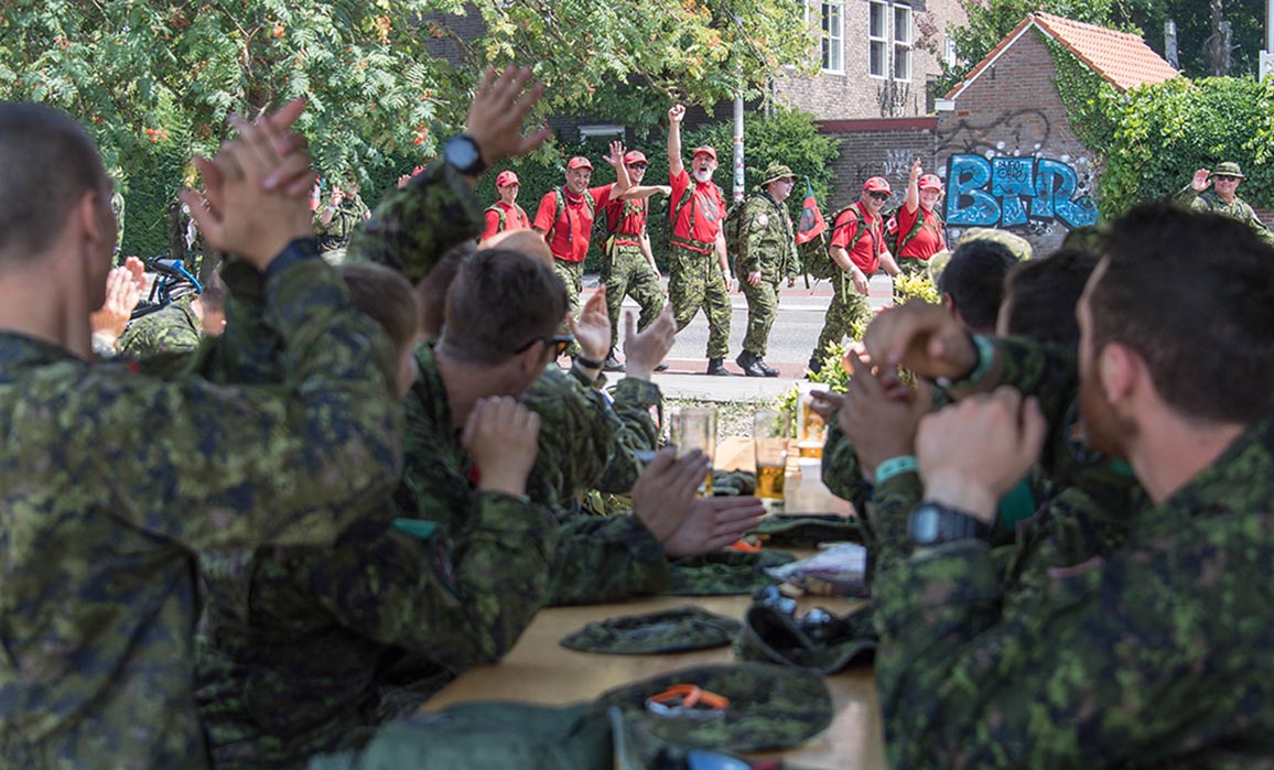 Le 2e Groupe de patrouilles des Rangers canadiens, l'une des 14 équipes du contingent canadien de la Force opérationnelle interarmées Nimègue, salue des marcheurs près de la ligne d'arrivée à Nimègue aux Pays-Bas, le 17 juillet 2018.