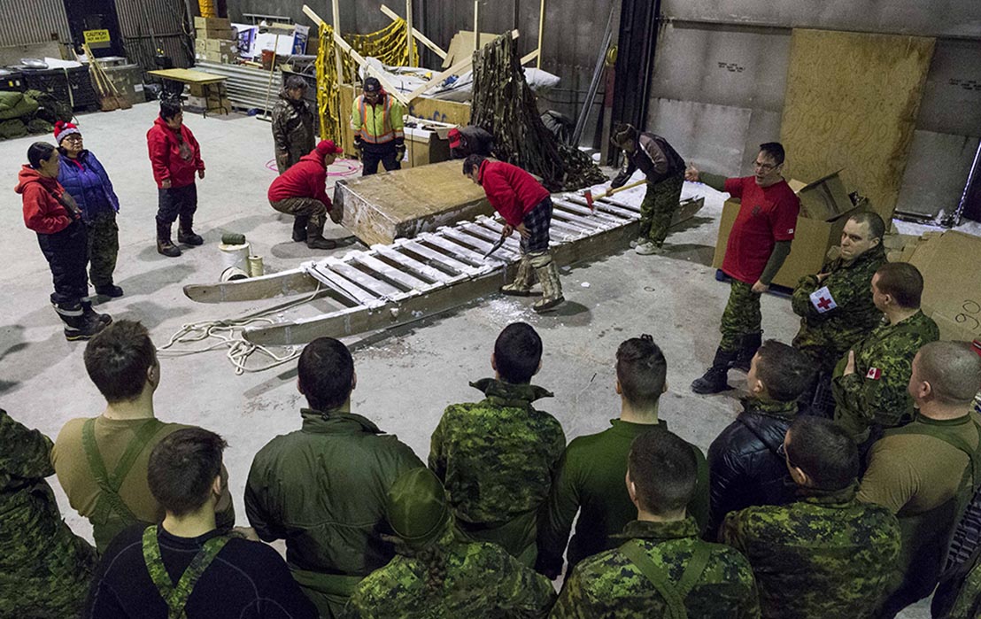 Des membres du 1er Groupe de patrouilles des Rangers canadiens montrent à des membres du 12e Régiment blindé du Canada en déploiement comment préparer un qamutik, à Hall Beach, au Nunavut, au cours de l’opération NUNALIVUT 2017, le 23 février 2017. Photo : Sgt Jean-François Lauzé, technicien en imagerie de la Force opérationnelle