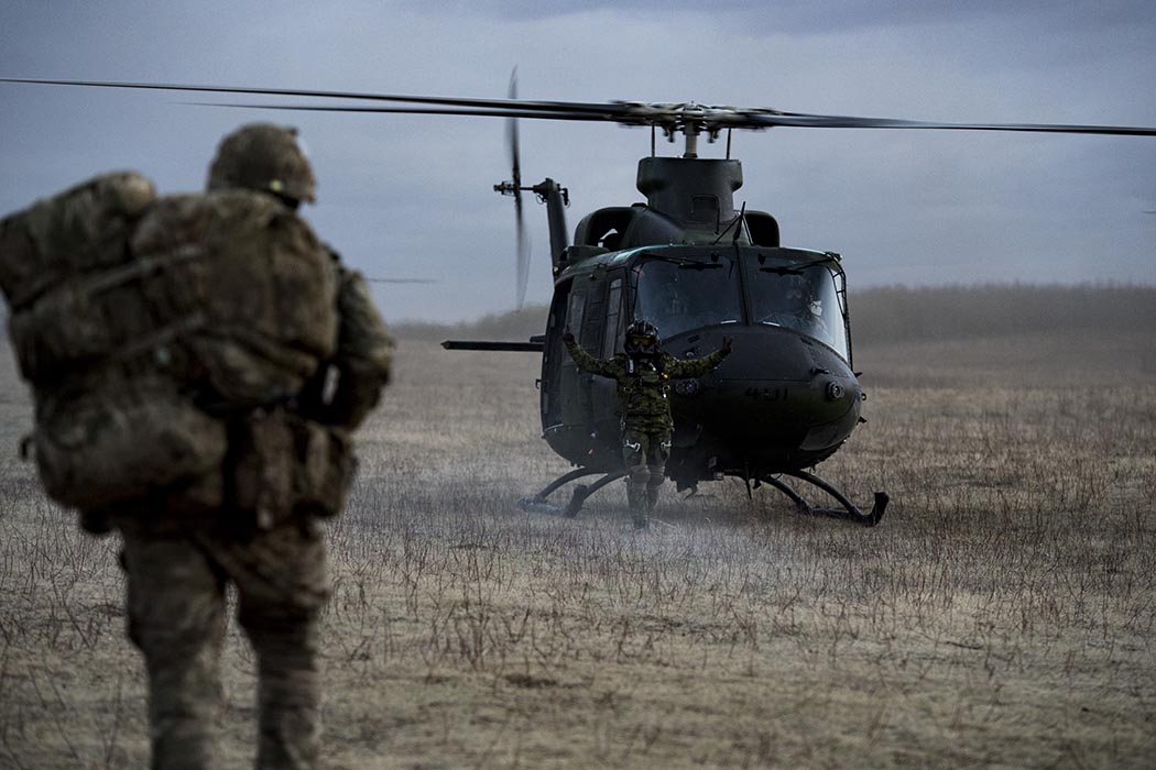 A Flight Engineer from a CH-146 Griffon Helicopter directs members of the British Army 1st Battalion, The Rifles during Exercise MAPLE RESOVE at 3rd Canadian Division Support Base Garrison Wainwright, Alberta on May 1, 2021.