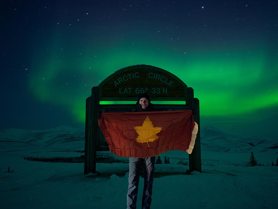 Drapeau de la 5e Division du Canada tenu devant le panneau du cercle arctique
