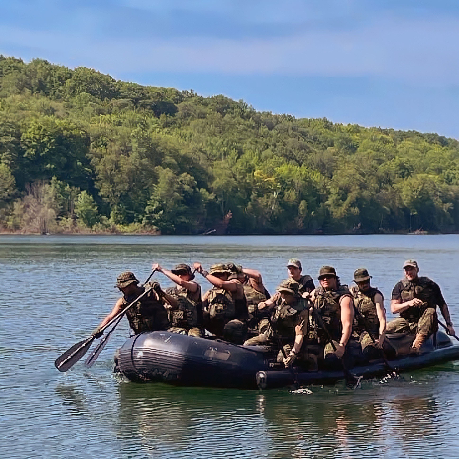 Several soldiers are paddling an assault boat.