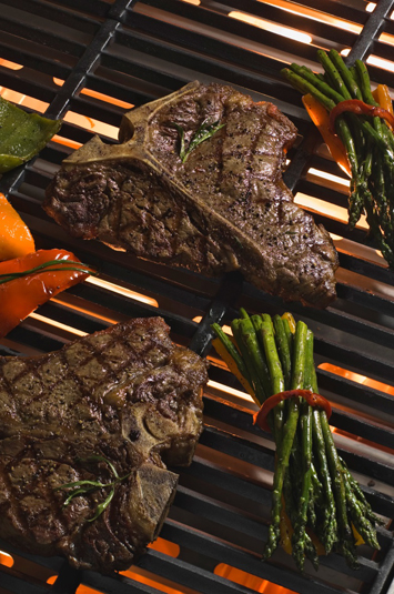 T-Bone steak with peppers and asparagus roasting on a grill