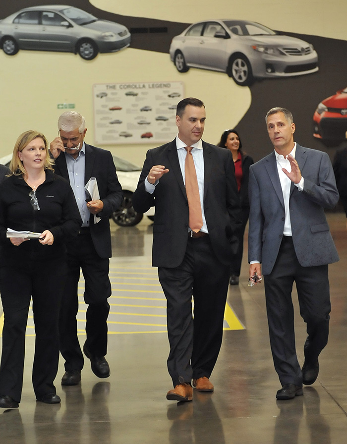 Erin Buchanan, Assistant General Manager, Toyota Motor Manufacturing Canada (TMMC) (far left); Ray Tanguay, Chairman, TMMC (left); and Greig Mordue, General Manager, TMMC (far right), give Industry Minister James Moore a tour of the Toyota Canada assembly plant in Cambridge, Ontario.