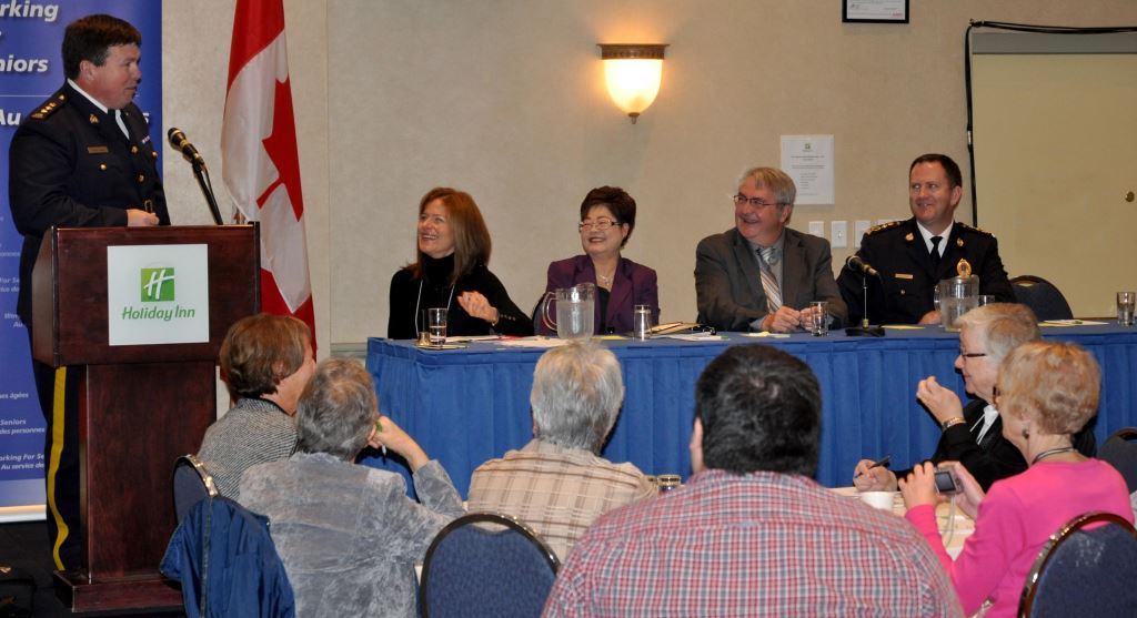 At the podium: Chief Superintendent Andrew Boland, Officer in Charge of Criminal Operations, RCMP B Division. 
At the table: Ms. Jean Cook, Conference Facilitator; Minister Wong; the Honourable Clyde Jackman, Minister of Seniors, Wellness and Social Development for Newfoundland and Labrador; and Chief William Janes, Chief of Police, Royal Newfoundland Constabulary.

