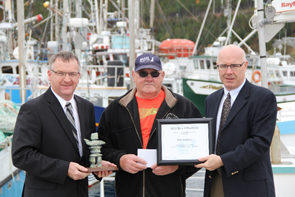 Senator Manning presents a 2013 Small Craft Harbours Prix d'Excellence to Mike Hawkins. From left to right: Senator Manning, Mike Hawkins and Bill Goulding, Regional Director for Small Craft Harbour in Newfoundland and Labrador.