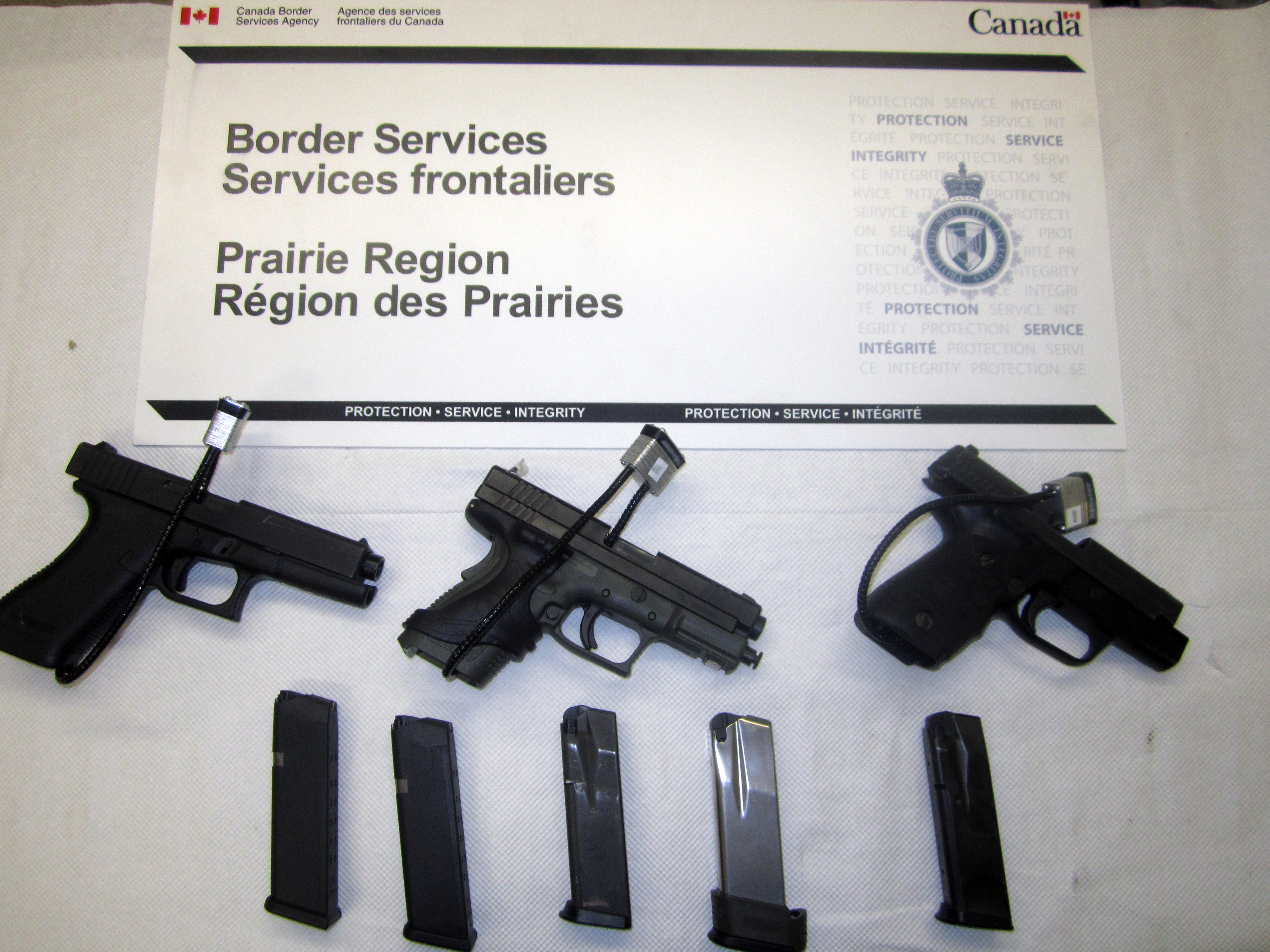 The three pistols and five overcapacity magazines seized at North Portal on June 26, resulting in a Customs Act conviction.