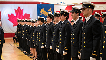 Canadian Coast Guard Academy officer cadets in uniform stand in rows inside a gymnasium.