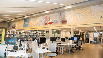 Modern library with maps, ship murals, workstations, computers and bookshelves.