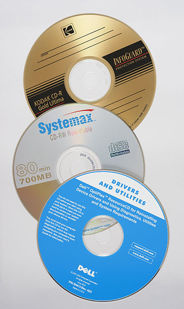 Trois CD. De haut en bas, un CD inscriptible Kodak, un CD réinscriptible Systemax et un CD non inscriptible Dell contenant des logiciels.
