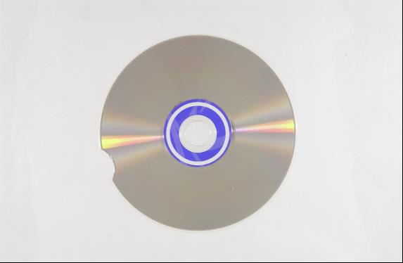 Base side view of an audio CD with a small missing piece on the exterior portion of the disc