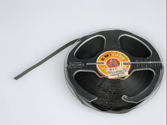 A quarter inch audio reel tape with a broken plastic flange and damaged tape in the area where the flange is damaged