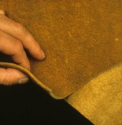 Une main tient une peau ambre, qui repose sur une peau d'un jaune plus pâle.