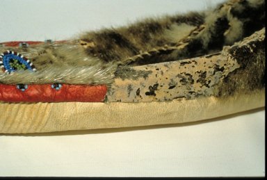 Detail of a sealskin fur moccasin, showing a large area where the fur hairs are completely missing due to insect attack; as well small bits of the seal skin have been eaten away by insects.