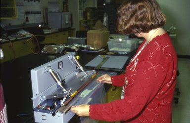 A conservator seals two sheets of oxygen-barrier film using a heat-sealer machine.