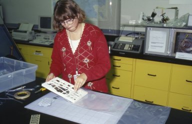 A conservator inserts the mounted objects in their support into the pouch.