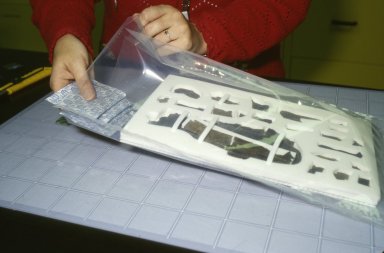 A conservator inserts oxygen absorber sachets into the pouch.