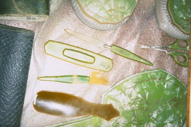 Four small tools are laid out on a piece of fabric. Only the handle of the buttonhook remains. The fabric is covered with a residue from the corroded metal.