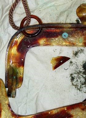 An enlarged view shows green discolouration on the tortoiseshell handle and a green powdery residue on the surrounding cloth.