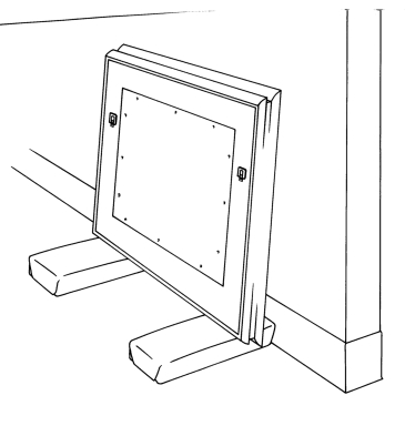 Un tableau encadré accoté contre un mur. Deux blocs matelassés sont placés près des bords, sous la partie inférieure du cadre, de façon à soulever le tableau du sol.