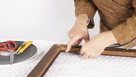 Photograph of a person attaching a self-adhesive polyethylene foam padding to the rabbet.