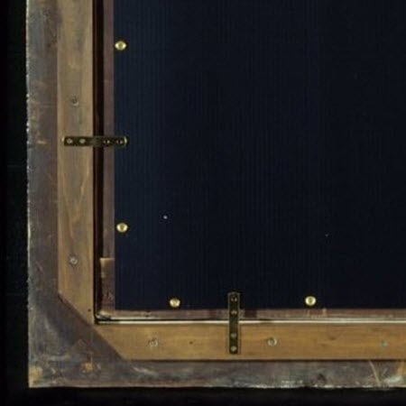 Photograph of a framed painting, shows a backing board attached with screws and the painting secured in the frame with brass mending plates.