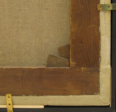 A detail of the back of a stretcher corner showing two wood keys inserted into the lower left corner joint of the stretcher