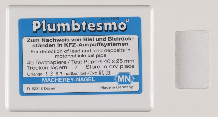 La boîte est étiquetée : Plumbtesmo for the detection of lead, test papers 40 by 25 mm, Macherey-Nagel. Le papier réactif est un rectangle blanc.