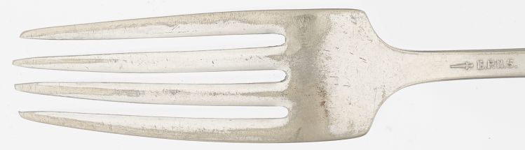 Tines of a dinner fork. Where the bright silver has worn away, the underlying metal is a dull gray.