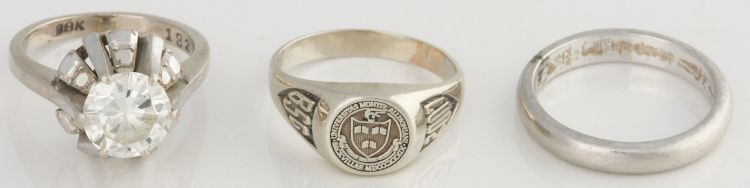 De gauche à droite : anneau en métal blanc serti d'un seul diamant et portant la marque 18K, bague d'école et anneau en métal blanc uni