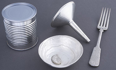 De gauche à droite : boîte de conserve, bol en étain moderne, entonnoir et fourchette