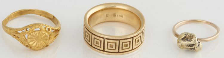 De gauche à droite : bague en métal jaune vif, anneau jaune à motifs portant la marque 18K et pépite d'or montée sur un anneau d'or uni