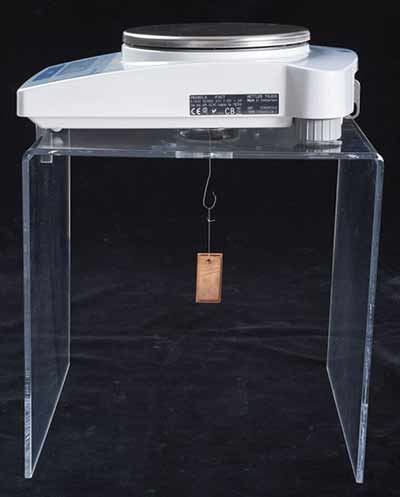 Rectangular coupon of pure copper being weighed in air.