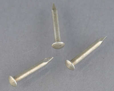 Three brass escutcheon pins after being plated with silver using a silvering paste, now silver coloured