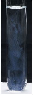 The liquid in the test tube has faint white swirls, visible against the black background.