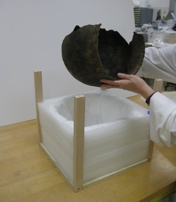 A person putting a ceramic vessel in a mount.