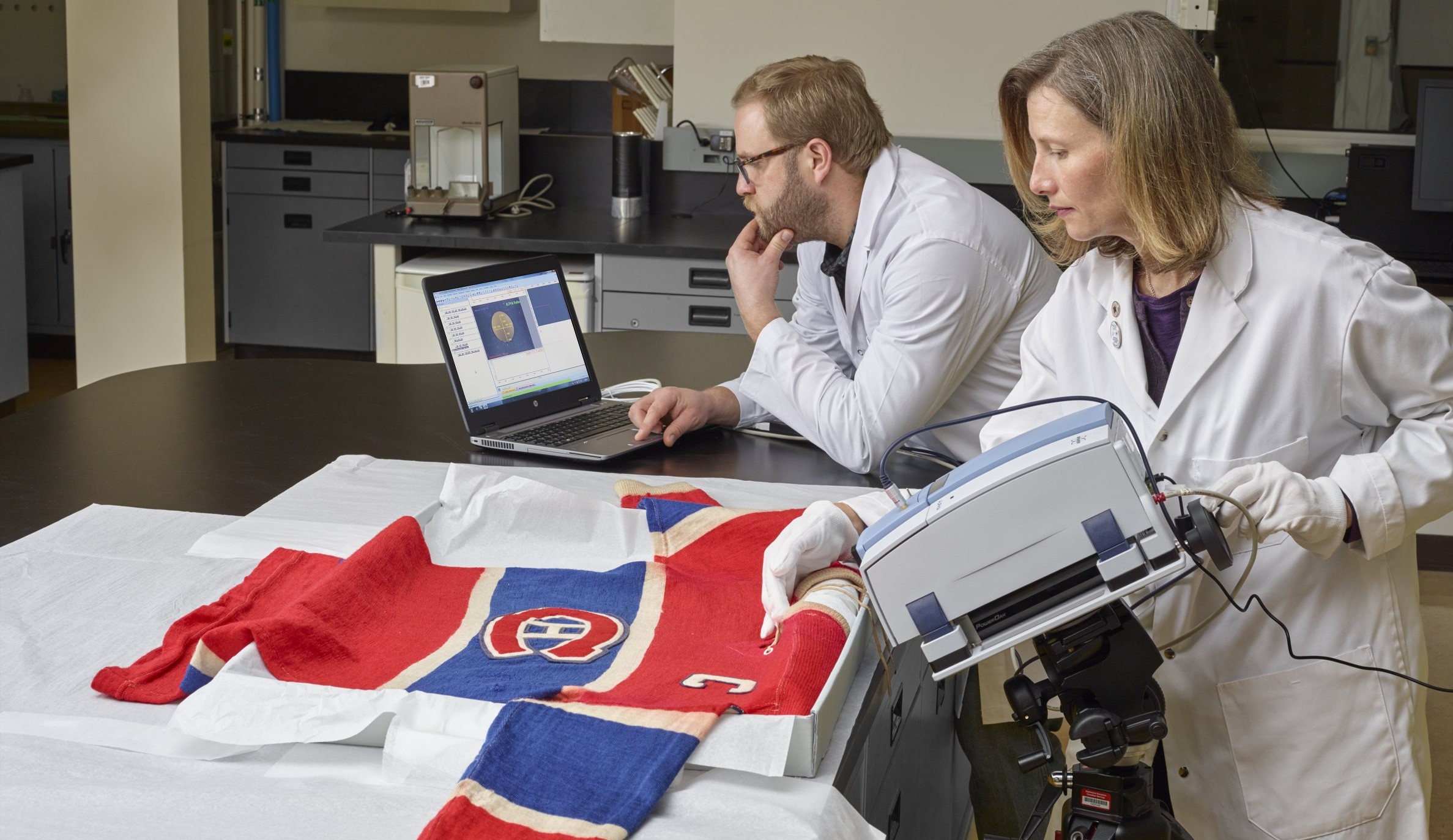 Photo: analyse d’une tache de sang sur le chandail de hockey de Maurice « Rocket » Richard, qui appartient au Musée canadien de l’histoire.