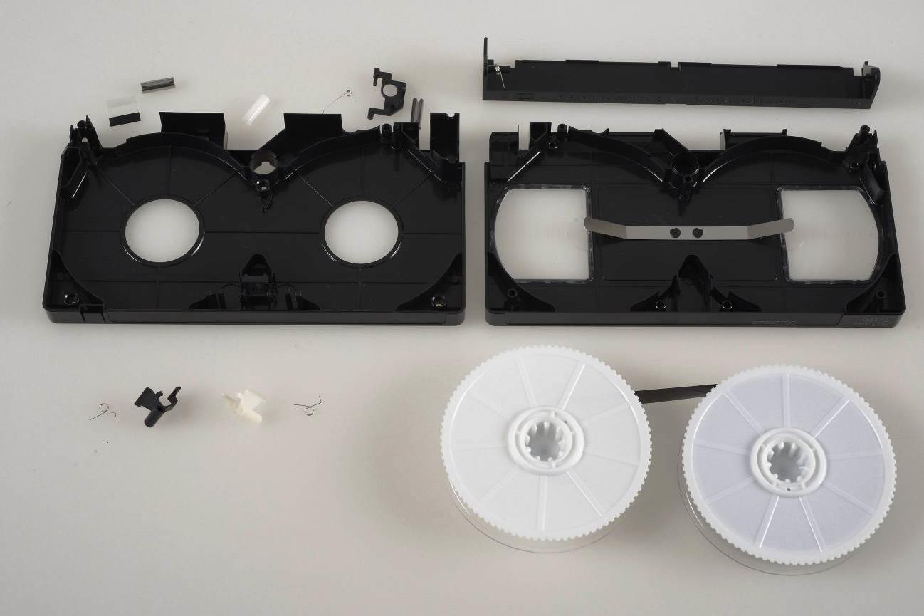 opened and dismantled VHS cassette illustrating the many small parts that exist