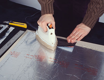 A hot iron is applied to plastic-laminated aluminum foil.