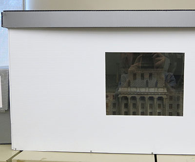 Une ouverture recouverte d’une pellicule Melinex sur le côté d’une boîte de rangement.