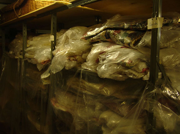 Storage of flat textiles, showing overcrowded shelves containing quilts before RE-ORG