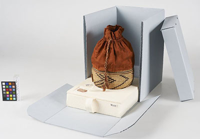 Panier avec pochette en tissu attachée à son rebord dans une boîte.