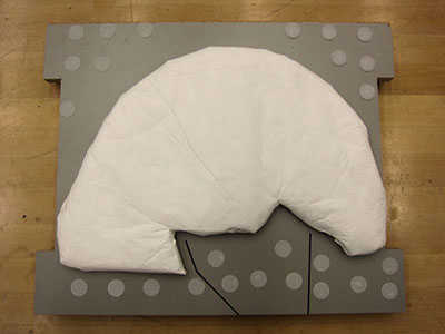 A solid base with padded polyethylene non-woven (Tyvek) cushion to support the lamp.