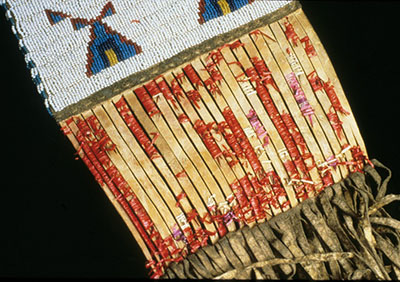 Quills, wrapped around strips of hide on a sash, are extensively damaged and unravelling.