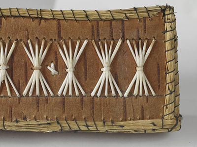 Detail of a birchbark and sweetgrass container with undyed porcupine quill decorations.