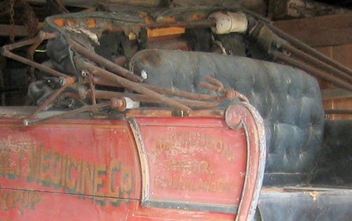 Une ancienne voiture hippomobile où il y a une mince couche de moisissure sur les sièges en cuir et des pièces en fer rouillées.