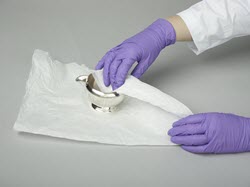 Silver object being wrapped in acid-free tissue paper.